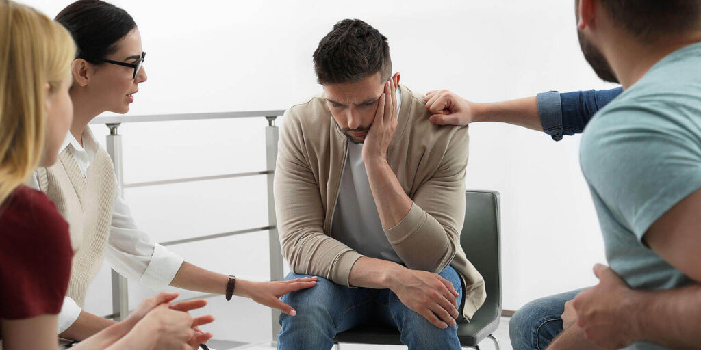 A photo of psychotherapist working with a drug rehab group at a therapy session indoors — leaving rehab early concept